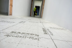 Maxxon Acousti-Mat sound control matting installed across a subfloor prior to gypsum underlayment application.